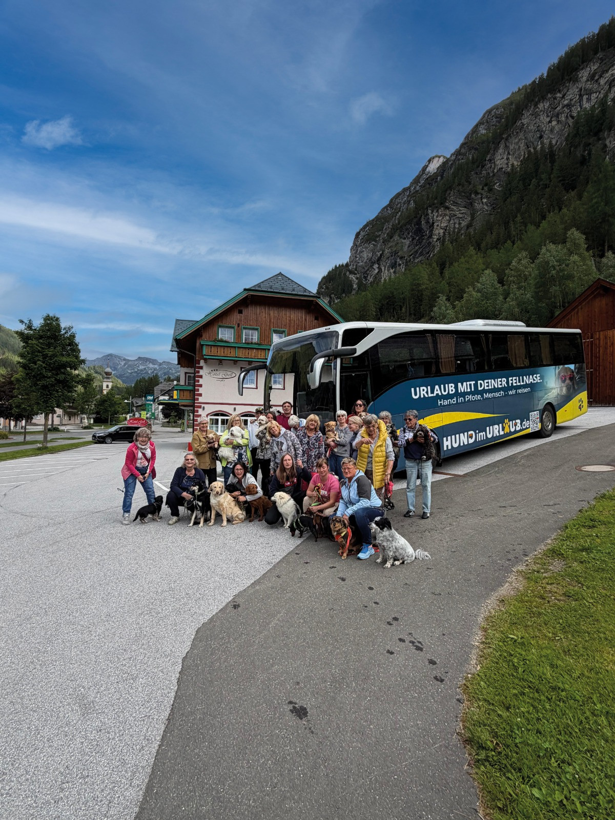 Reisegruppe mit ihren Hunden vor dem Reisebus von Hund im Urlaub in den Alpen